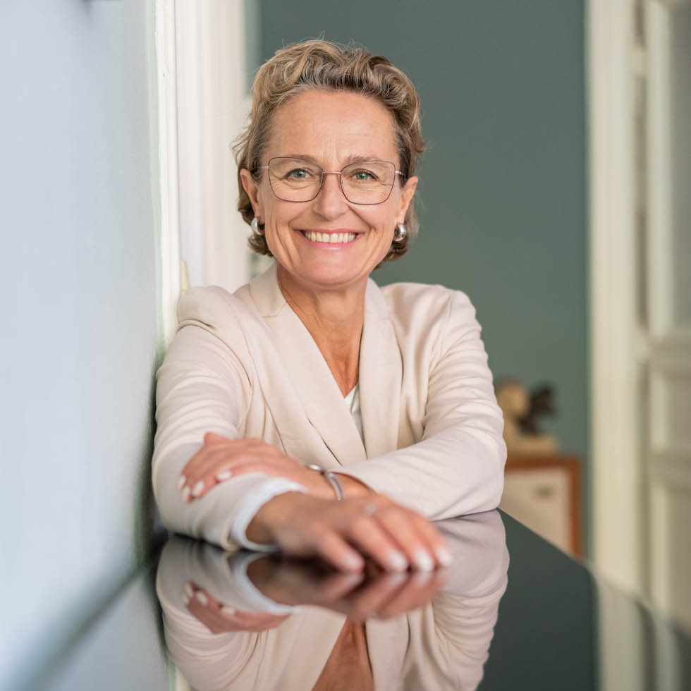 Frau in heller Kleidung lächelt in die Kamera