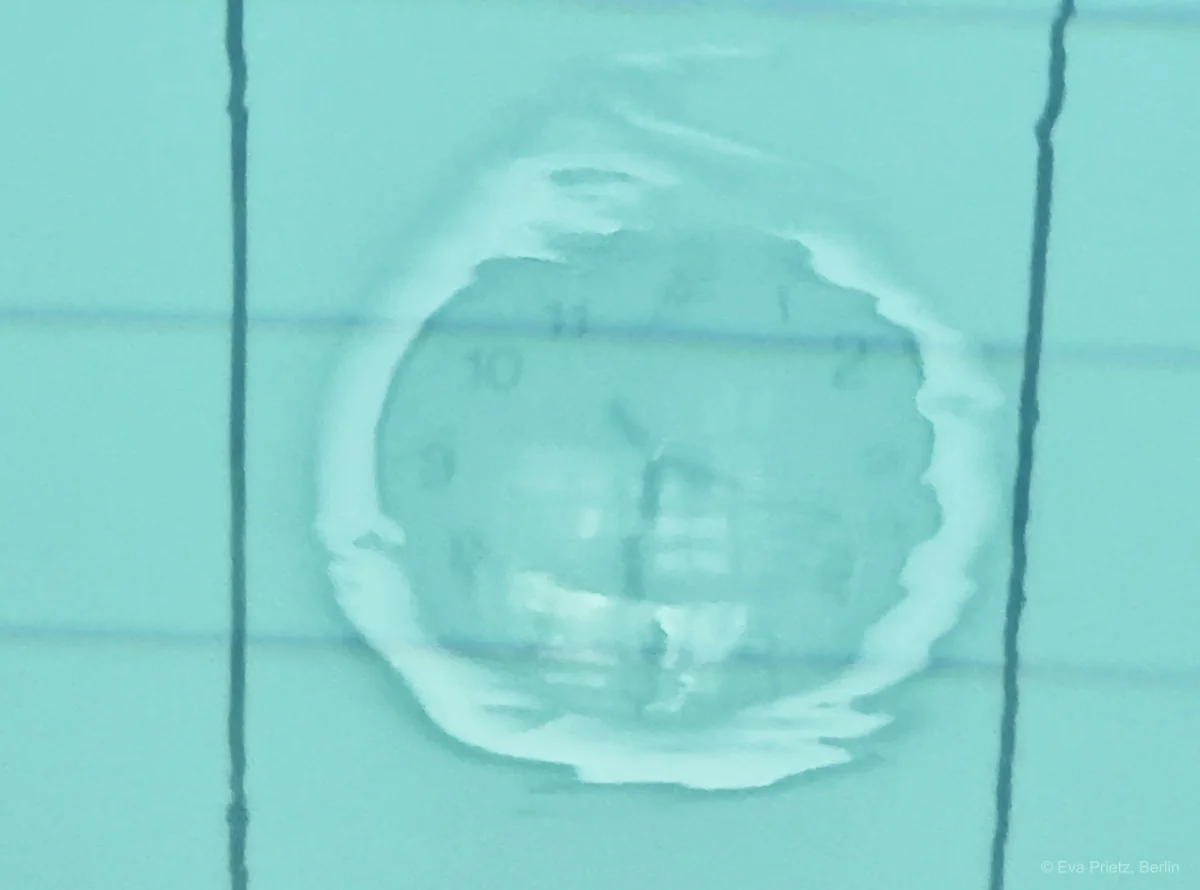 Abstrakte Wasserfotografie mit verschwommener Uhr als Sinnbild für Zeitqualität in strategischen Führungsklausuren und bewusster Kommunikation auf Geschäftsführungsebene